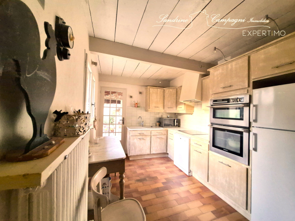 Kitchen in a renovated farmhouse with light-colored furniture and modern appliances.