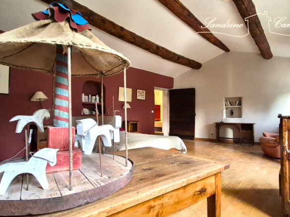 Interior of a bedroom with a wooden carousel and exposed beams.