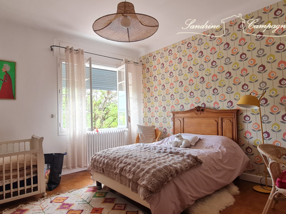 Bedroom in a renovated house with a double bed and a baby cot, decorated with colorful wallpaper.