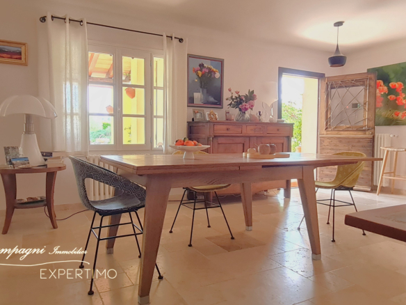 Interior of a renovated house with a wooden table and modern chairs, abundant natural light.