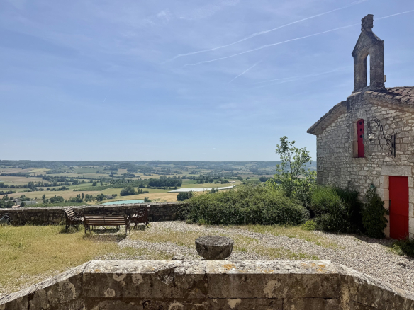 Vue panoramique depuis un domaine avec chapelle, surplombant une vallée à Penne-d'Agenais.