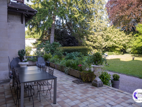 Terrace of a bourgeois house with garden furniture and wooded garden in Noyon.