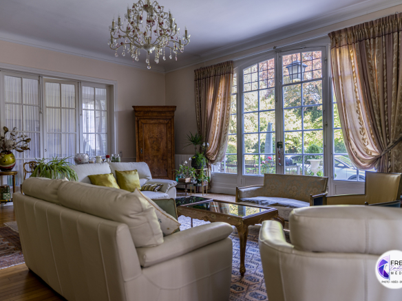 Interior of a bright living room with light-colored sofas and large windows.