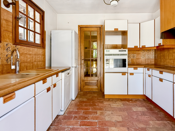 Spacious kitchen with wooden furniture and tiled floor in a family property.
