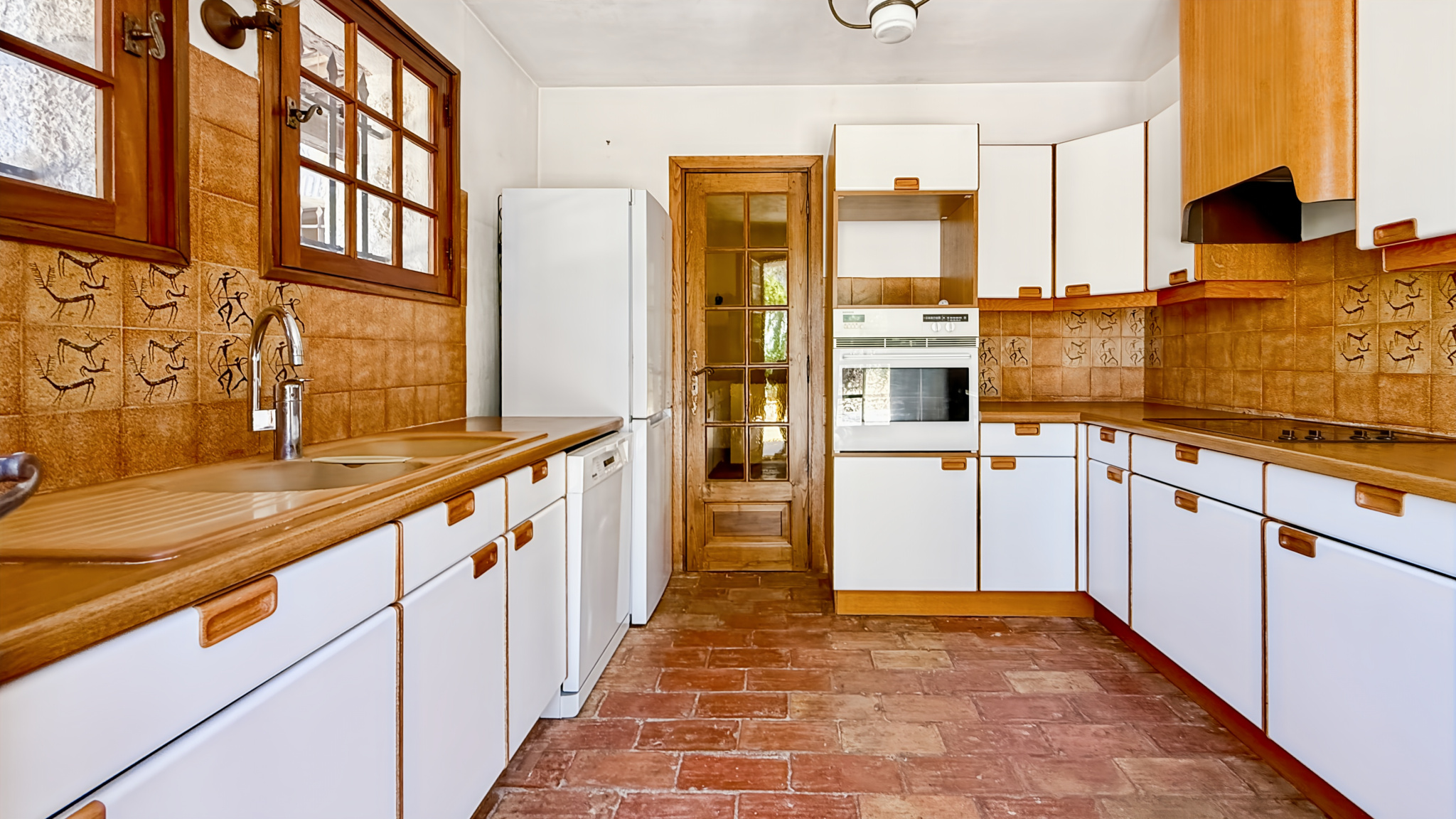 Spacious kitchen with wooden furniture and tiled floor in a family property.