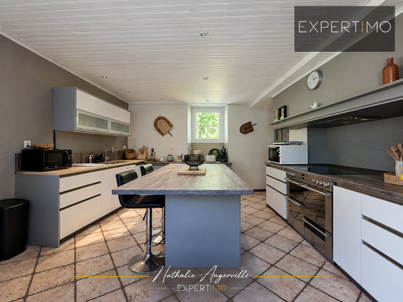 Cuisine moderne dans un ancien moulin réhabilité, avec îlot central et équipements contemporains.