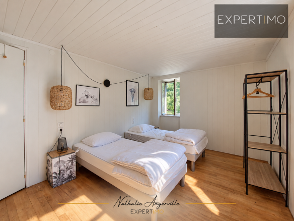 Chambre d'hébergement avec deux lits simples et décoration minimaliste.