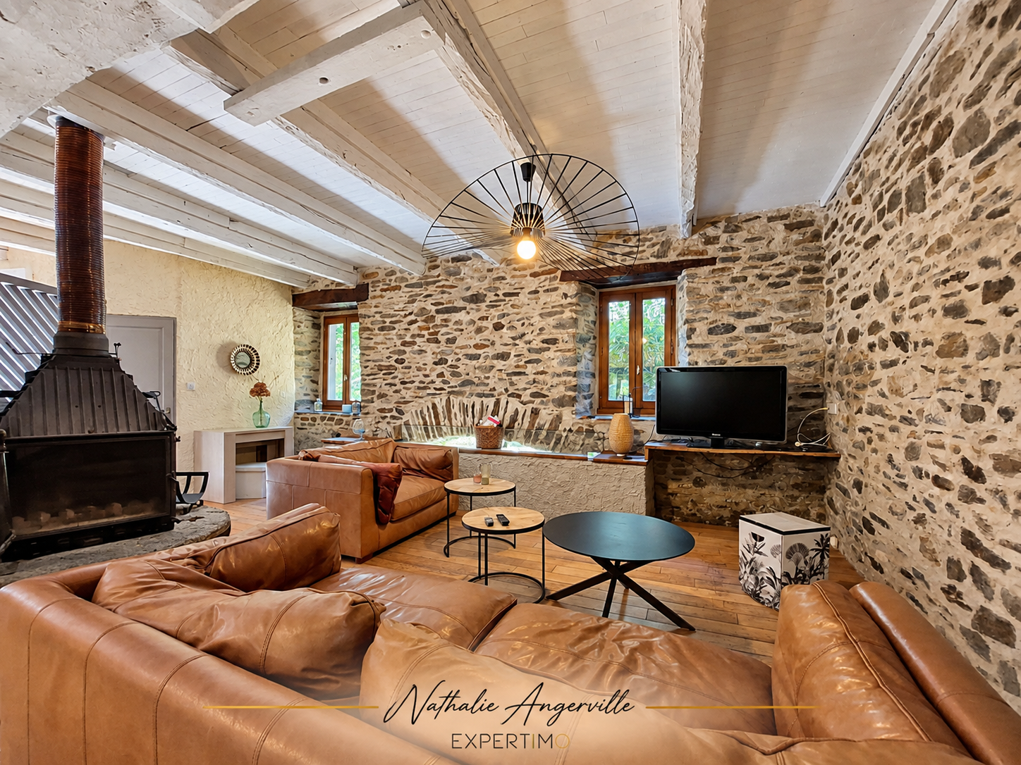 Intérieur d’un ancien moulin Intérieur d'un ancien moulin réhabilité avec un salon en pierre et bois, canapé et cheminée.