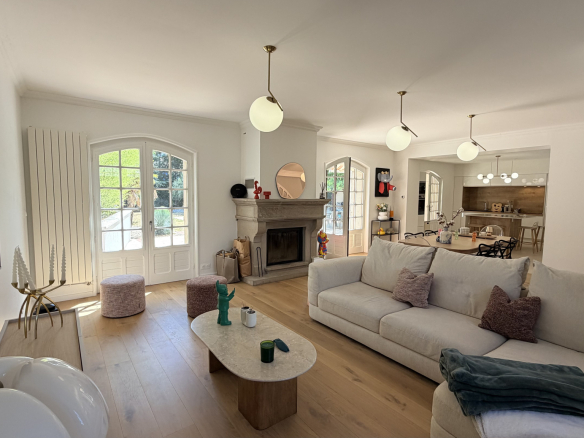 Interior of a renovated house with a bright living room, fireplace and open kitchen.
