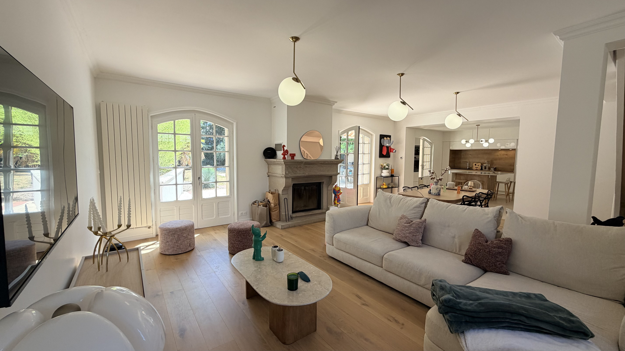 Interior of a renovated house with a bright living room, fireplace and open kitchen.