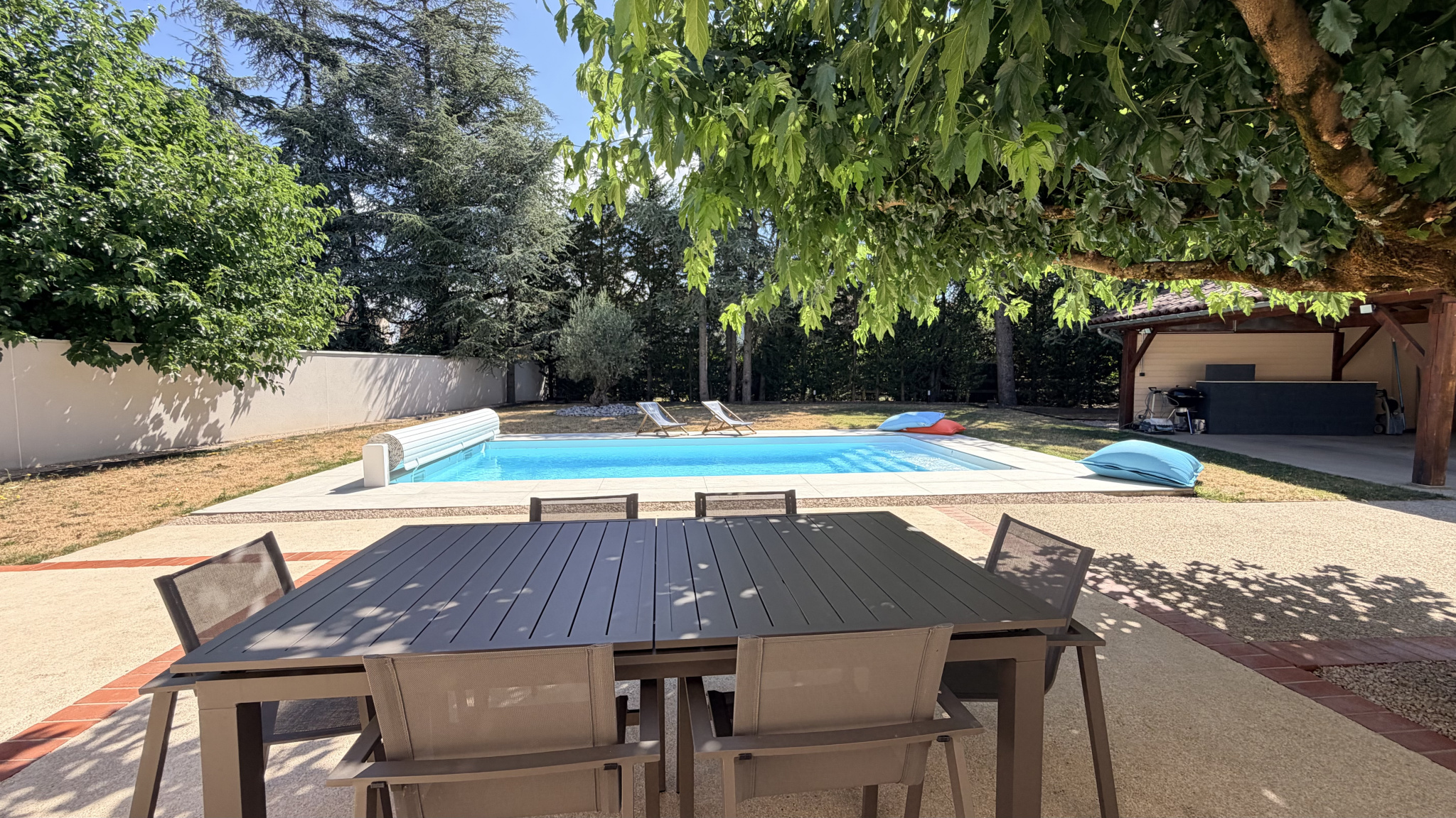 Terrace with table and chairs, swimming pool and sun loungers in Saint-Just-Saint-Rambert.