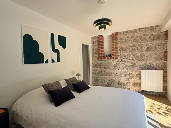Room in a renovated house with stone walls and a double bed.