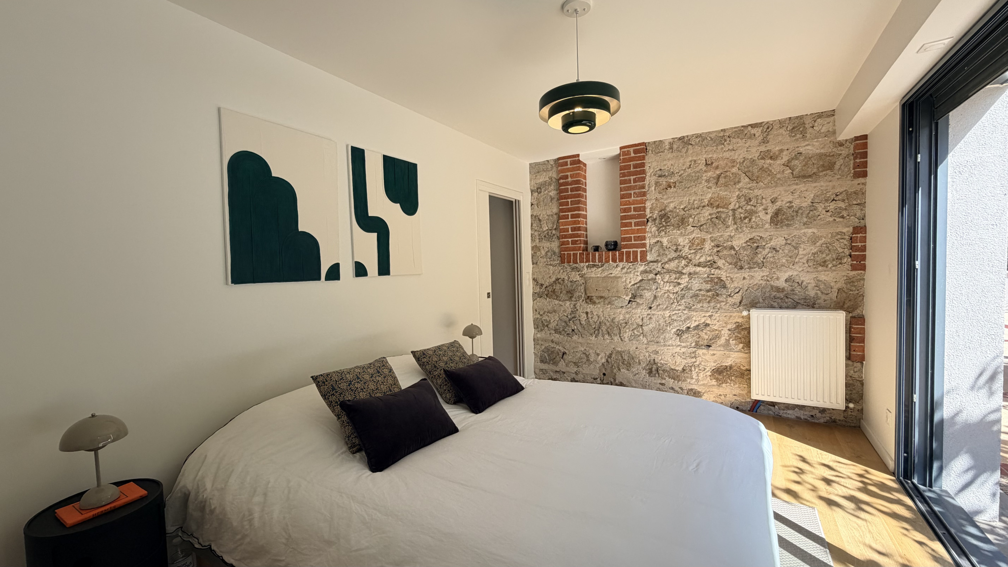 Room in a renovated house with stone walls and a double bed.