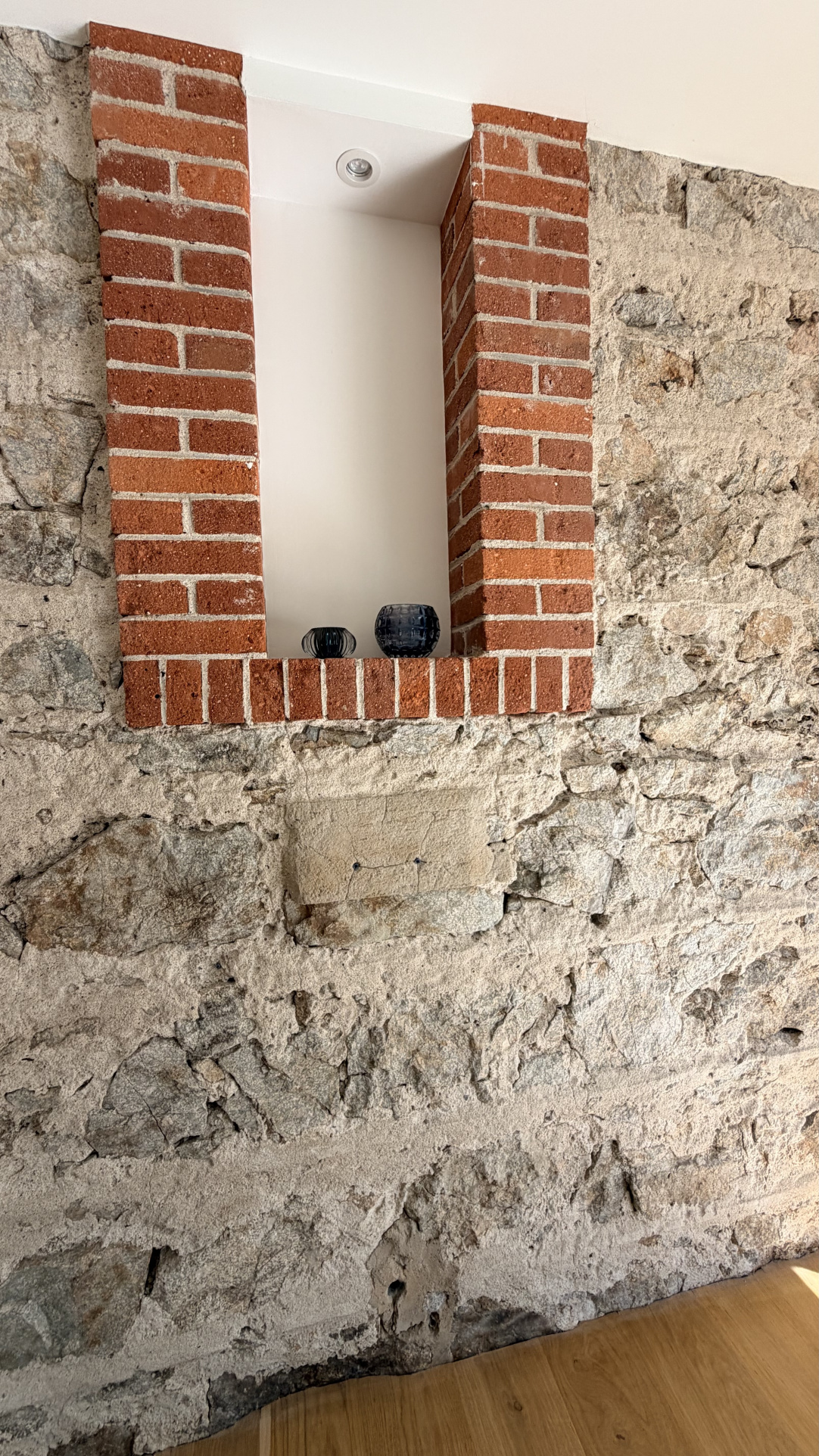 Stone wall with a brick niche, interior of a renovated house.