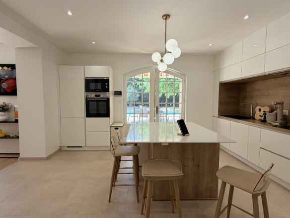 Modern kitchen with central island and integrated appliances in a renovated house.
