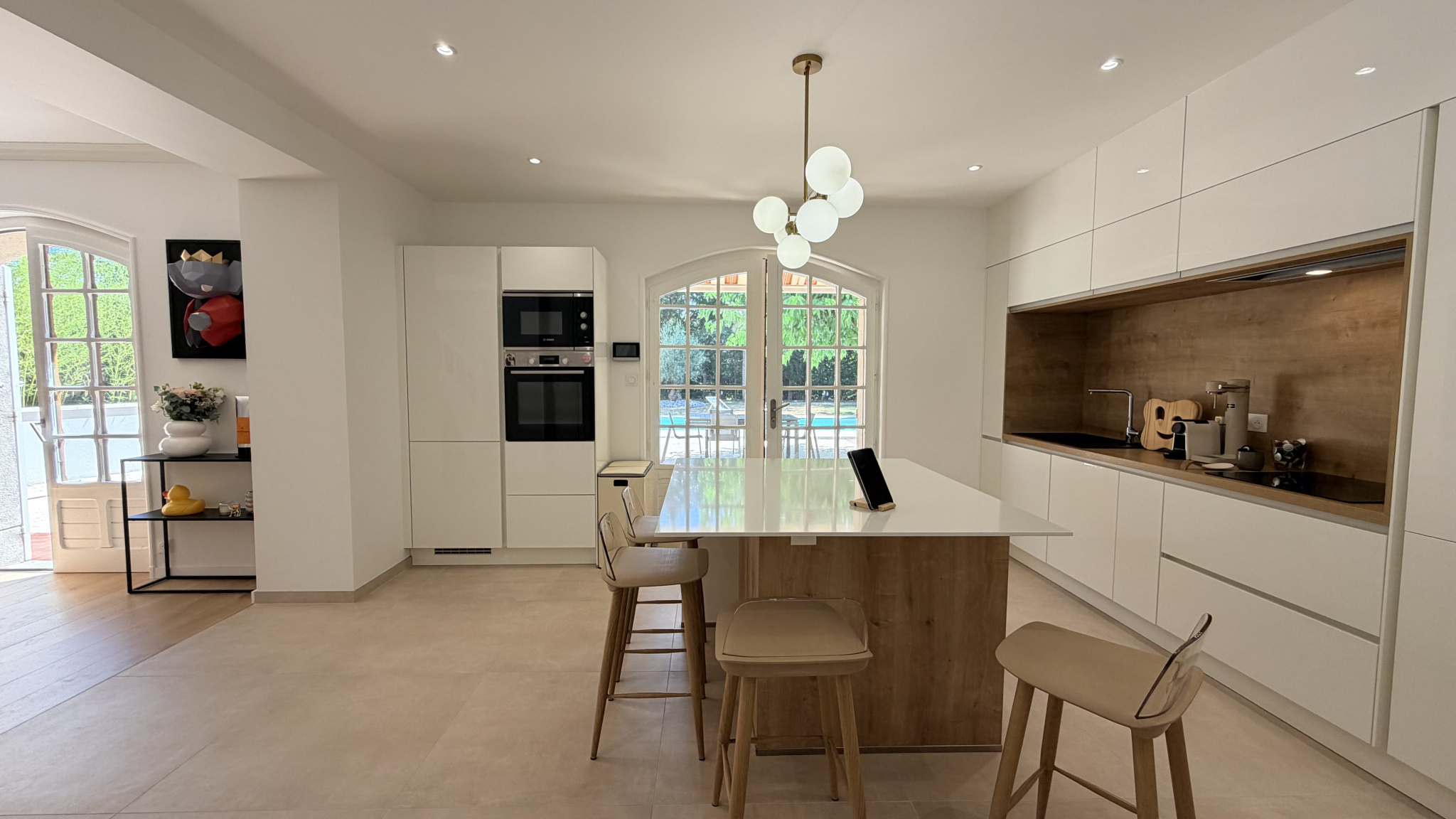 Modern kitchen with central island and integrated appliances in a renovated house.