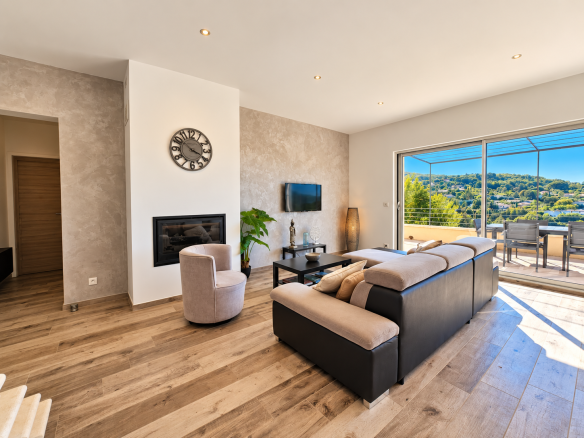 Intérieur d'une maison moderne avec salon lumineux, cheminée et vue sur le paysage.