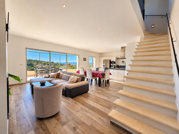 Intérieur d'une maison moderne avec salon lumineux et cuisine ouverte, vue sur le paysage.