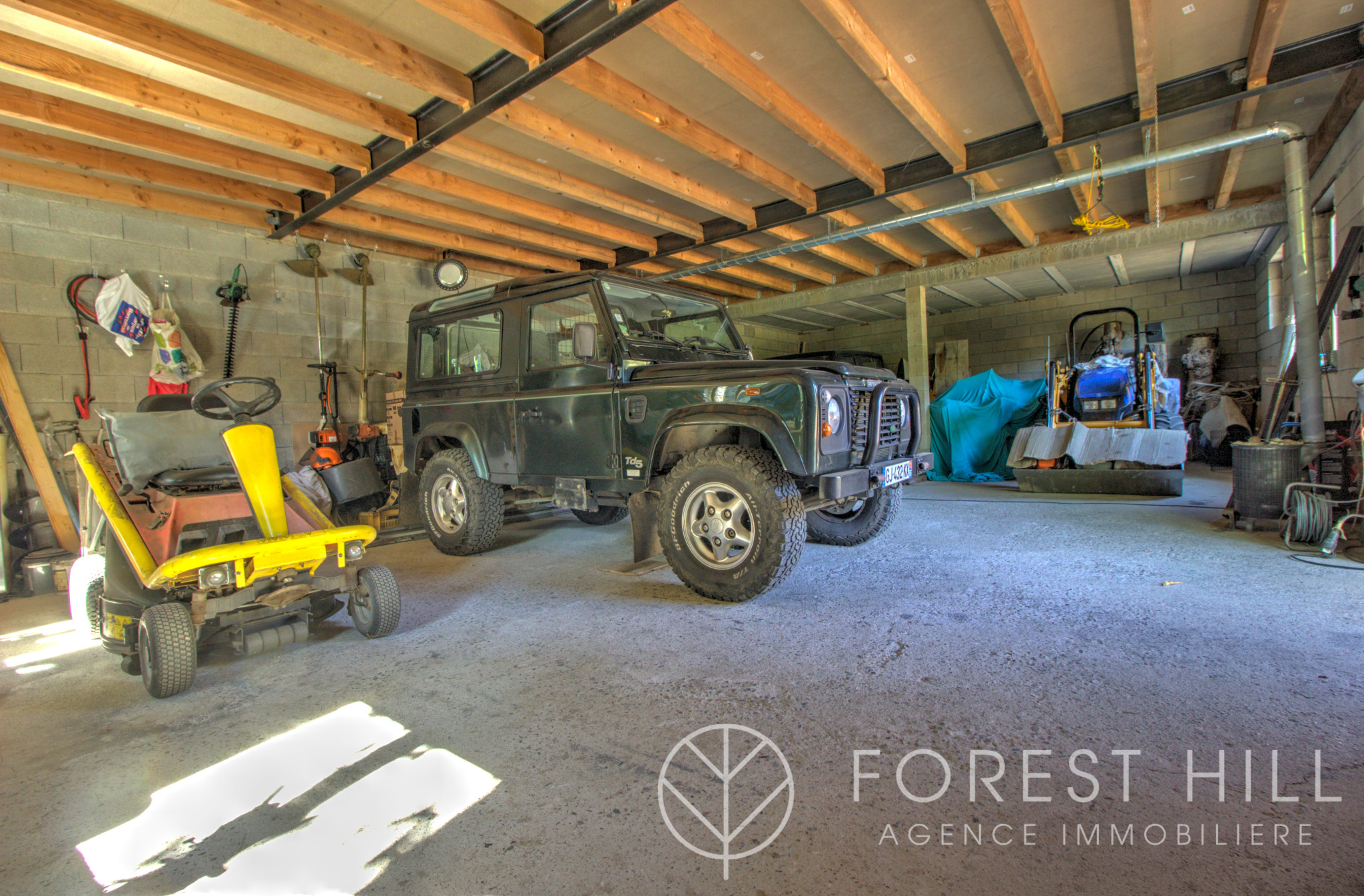 Intérieur de garage avec véhicule tout terrain Intérieur d'un garage avec un véhicule tout terrain et des équipements de jardinage.