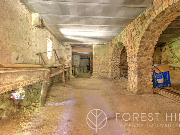 Intérieur d'un mas en pierre avec des murs en pierre apparente et un sol en terre battue.