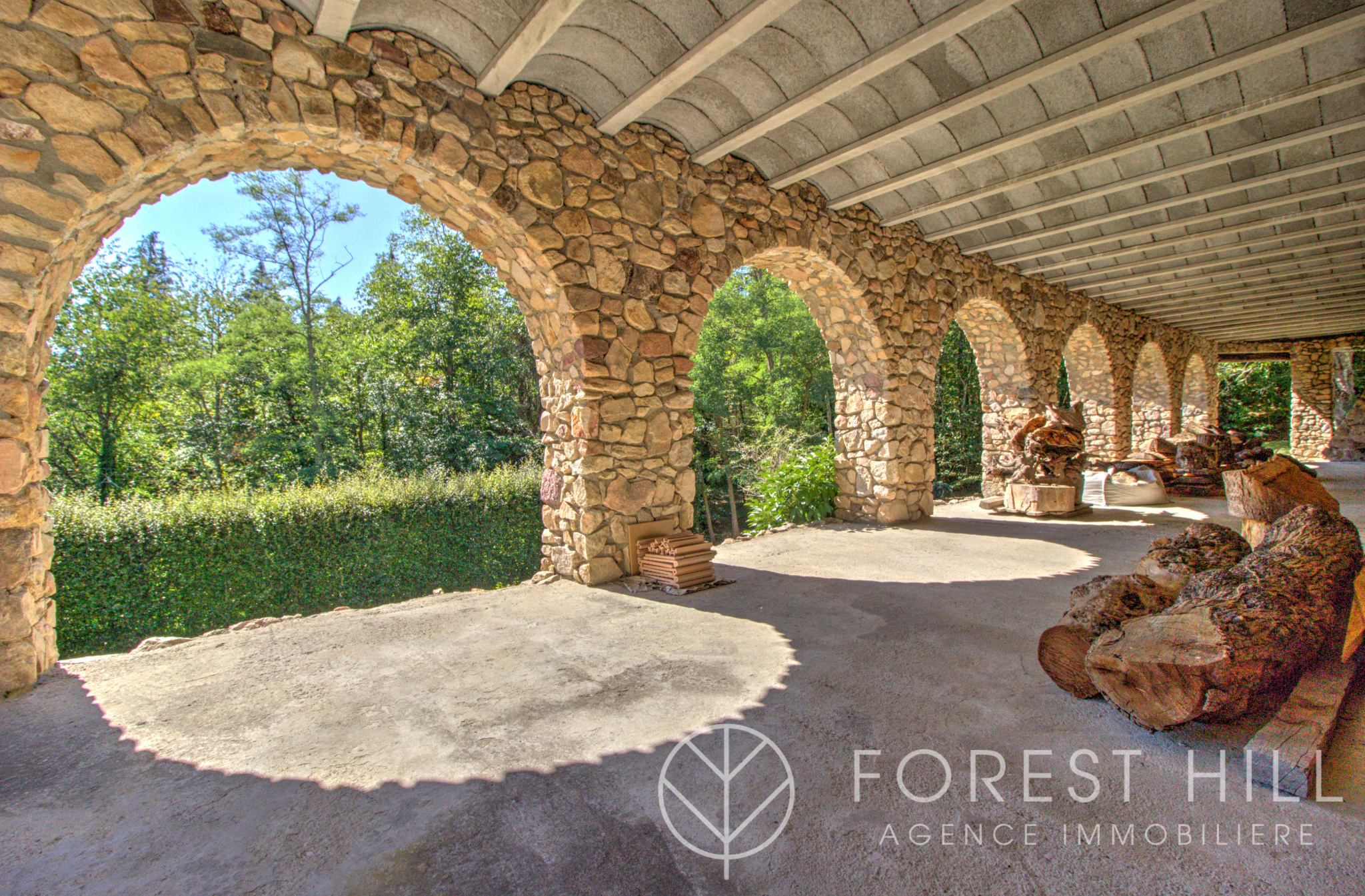 Terrasse en Pierre à Saint-Laurent-de-Cerdans Terrasse en pierre avec arches, entourée de verdure, à Saint-Laurent-de-Cerdans.