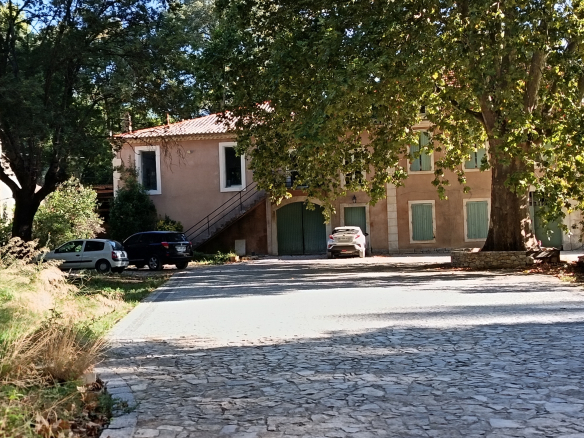 Ensemble immobilier avec salle évènementielle et logements à Poulx, entouré d'arbres.