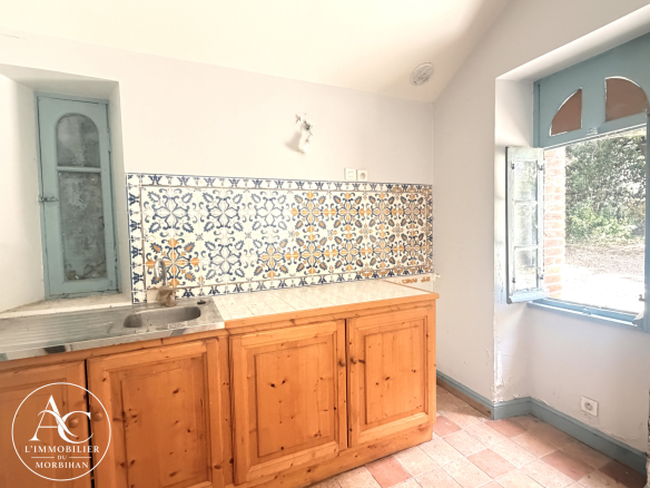 Kitchen in a farmhouse with wooden furniture and colorful tiles, windows open to the outside.