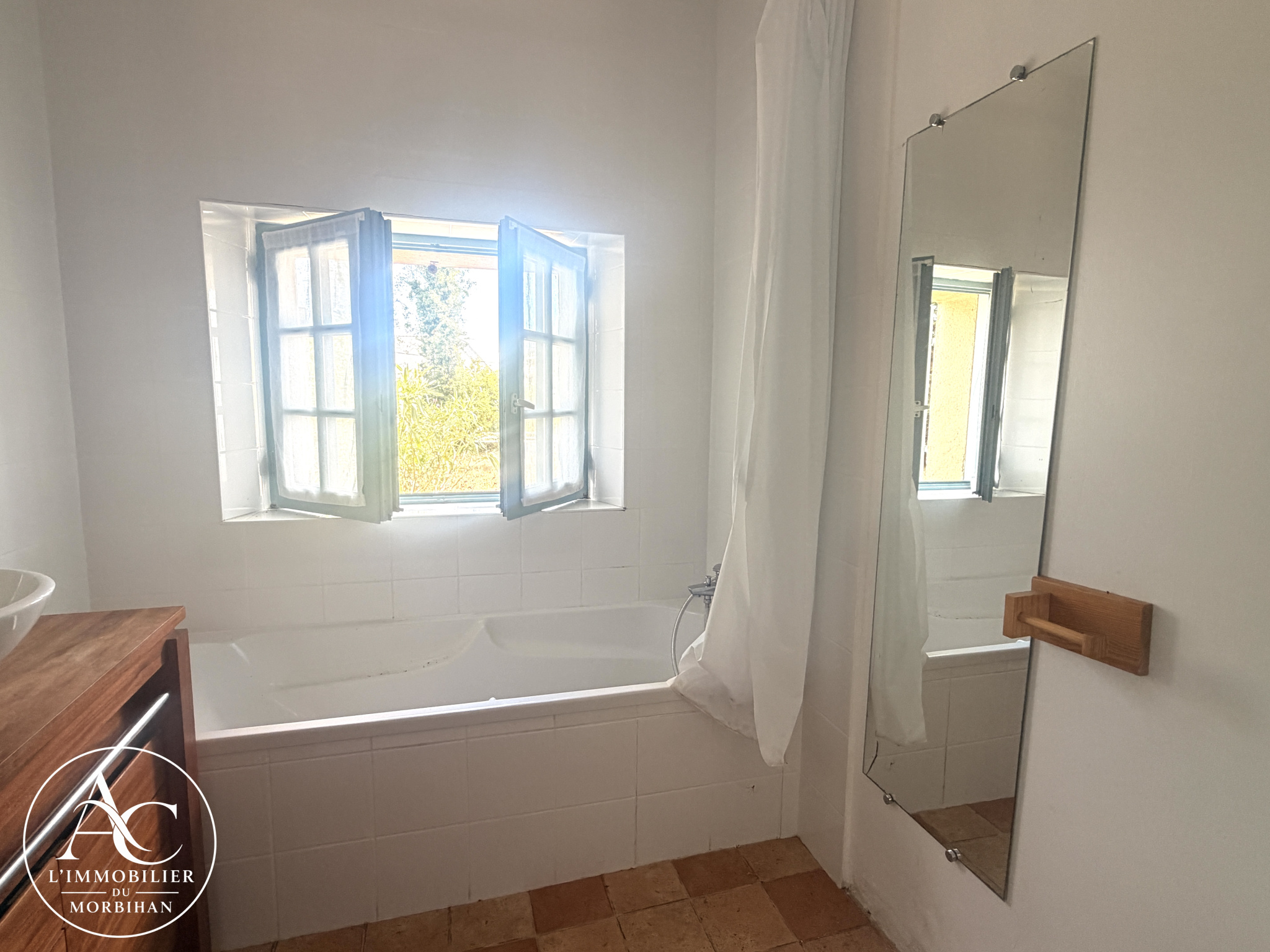 Bathroom in a farmhouse in Sarzeau Bright bathroom with bathtub and blue shuttered window.