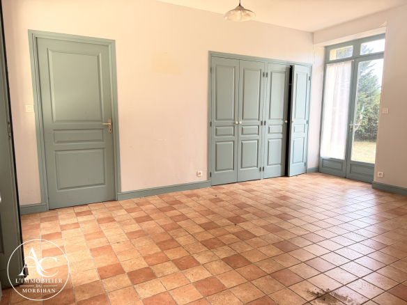 Interior of a longère (traditional farmhouse) with tiled floors and French doors opening onto the garden.