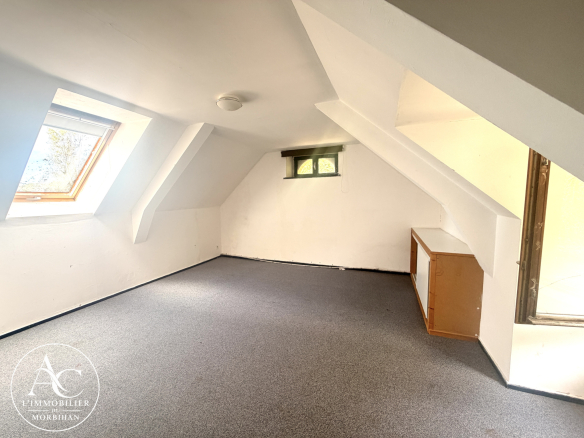 Interior of a longère (traditional farmhouse) with converted attic space, white walls and skylight.