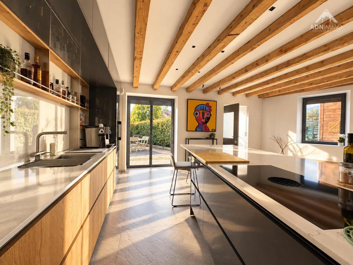 Cuisine moderne dans une maison rénovée Cuisine moderne avec îlot central et poutres apparentes dans une maison rénovée à Saint-Genis-Pouilly.