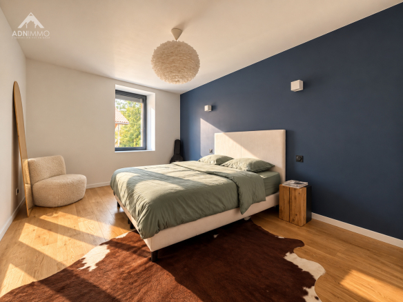 Chambre moderne avec lit double et décoration contemporaine, murs bleu foncé et parquet en bois.