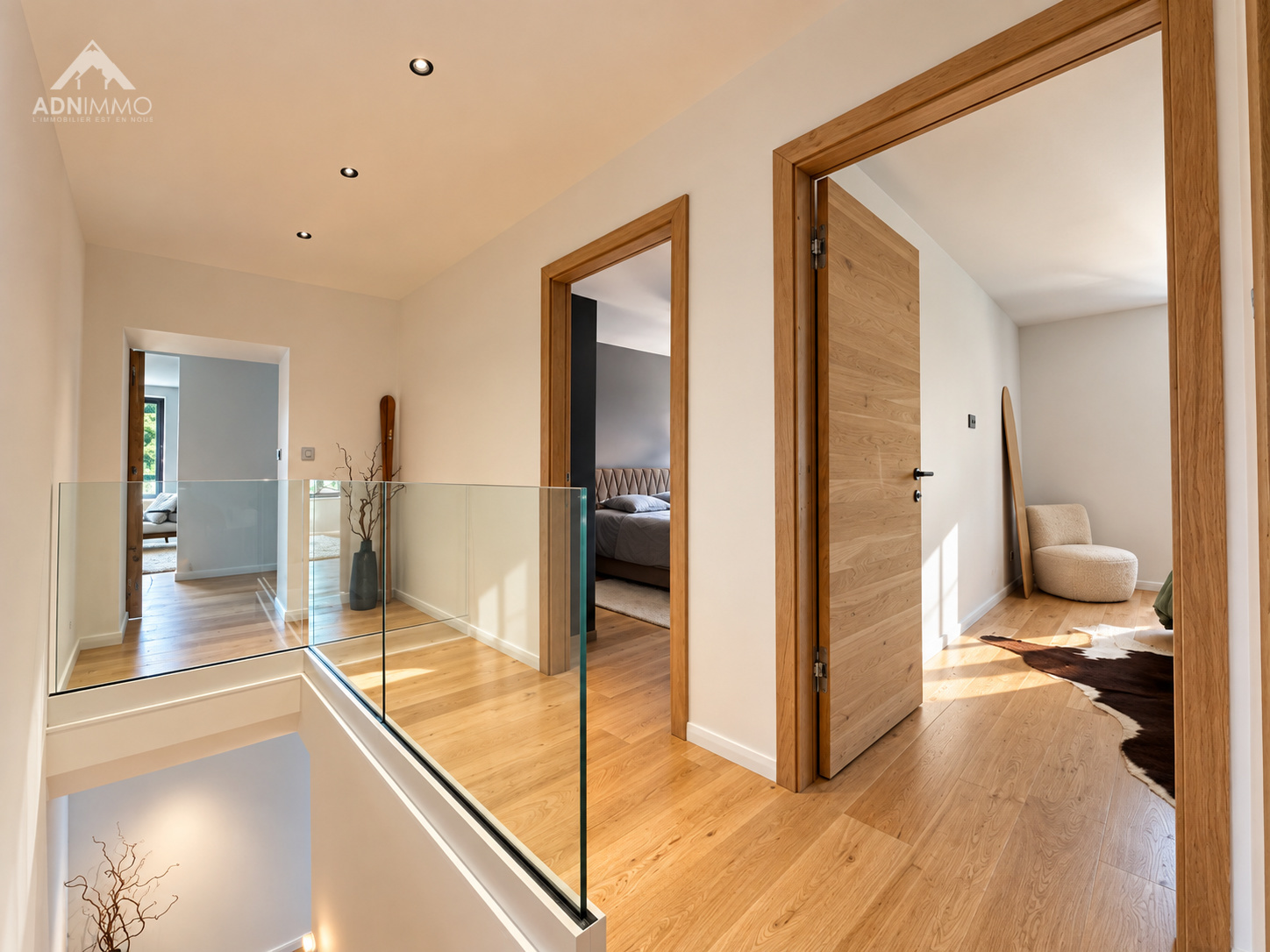 Intérieur d’une maison rénovée à Saint-Genis-Pouilly Intérieur d'une maison rénovée avec un couloir lumineux et des portes en bois.