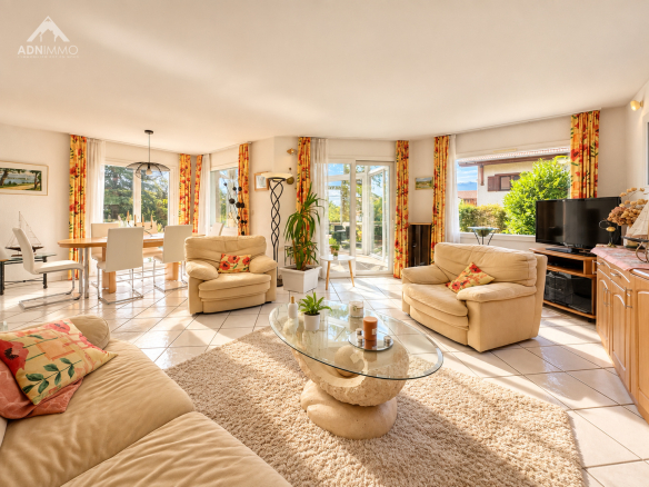 Intérieur lumineux d'une maison avec salon, salle à manger et accès à l'extérieur.