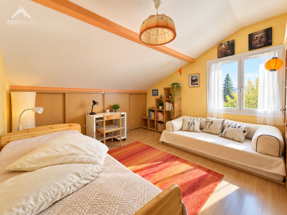 Chambre lumineuse avec lit, canapé et bureau dans une maison à Saint-Jean-de-Gonville.