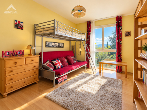 Chambre avec lit superposé et décoration britannique, fenêtre donnant sur un jardin.