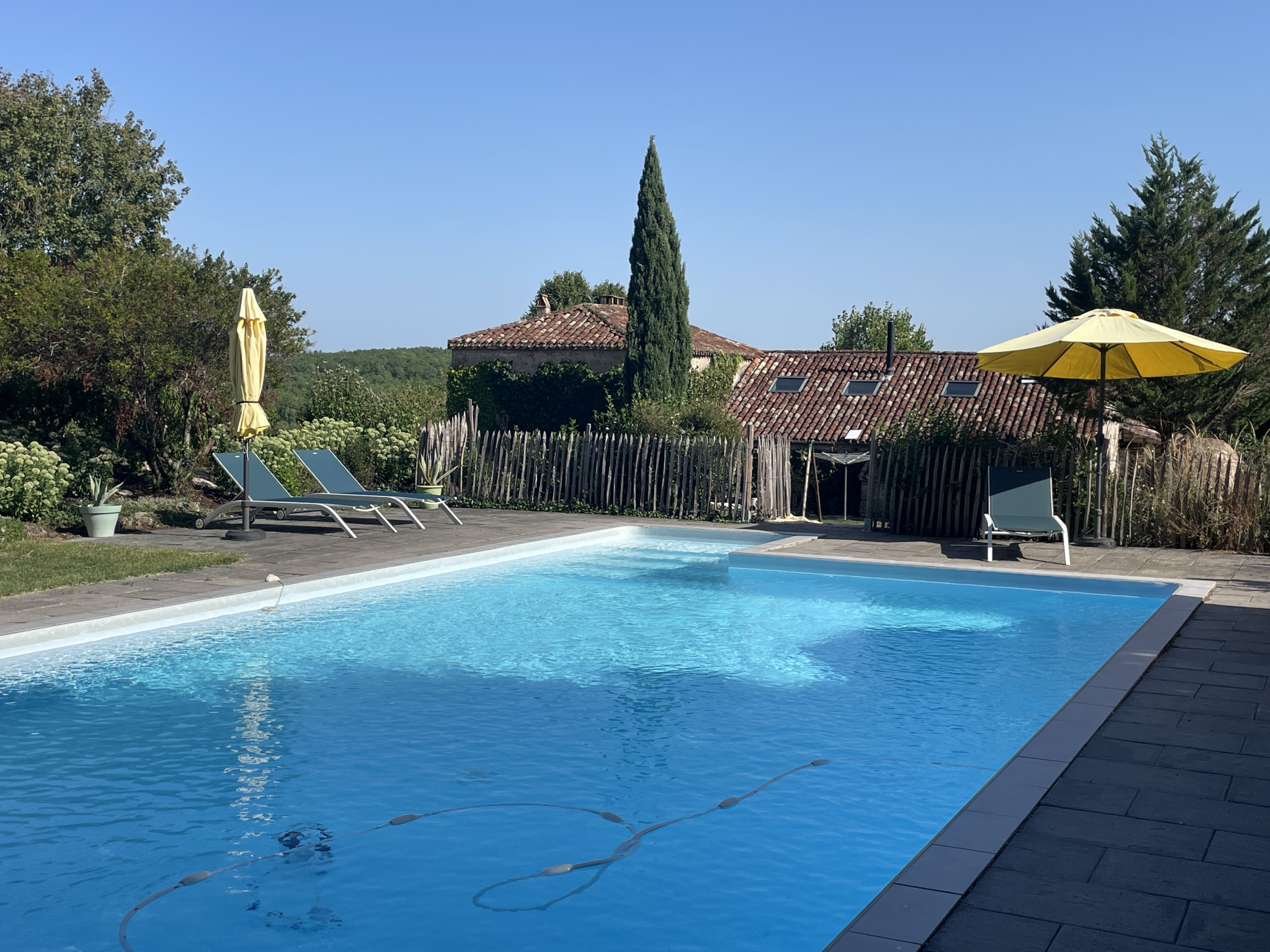Swimming pool at the estate in Tournon-d'Agenais Swimming pool on an estate with sun loungers and parasol, surrounded by greenery in Tournon-d'Agenais.