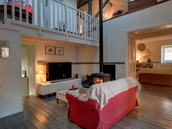 Interior of a stone house with living room, television and wood-burning stove.