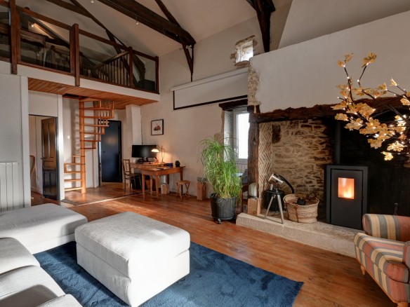 Interior of a stone house with living room, office and wood-burning stove.