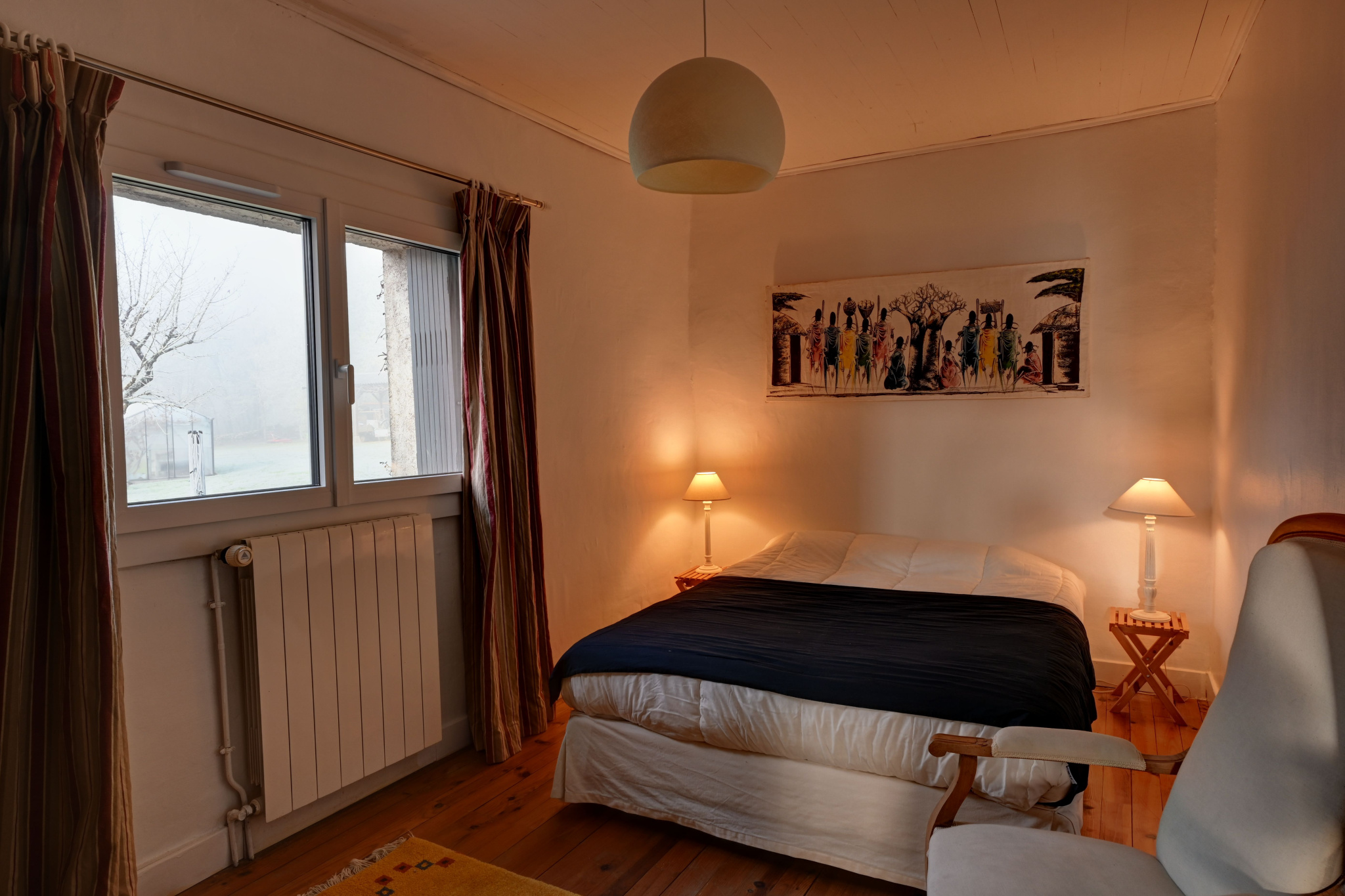 Room in an estate in Lot-et-Garonne Room in a stone house with bed, lamps and window overlooking a garden.