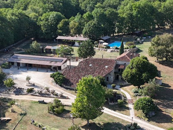 Aerial view of an estate with stone house, swimming pool and outbuildings in Tournon-d'Agenais.