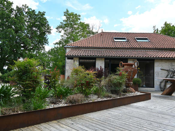 Wooden terrace with landscaped garden and stone house in Saint-Beauzeil