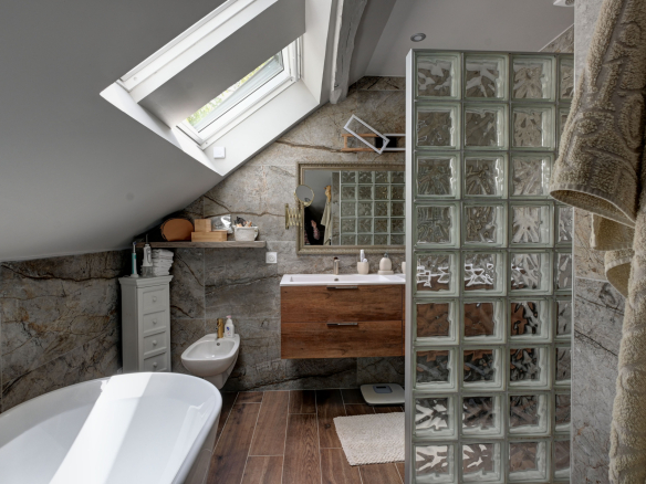 Modern bathroom with bathtub, wooden furniture and glass walls.
