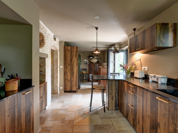 Modern kitchen with wooden furniture and stone worktop in a renovated house.