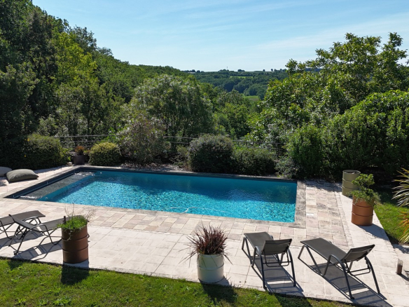 Swimming pool surrounded by sun loungers and greenery in a prestigious estate in Saint-Beauzeil.