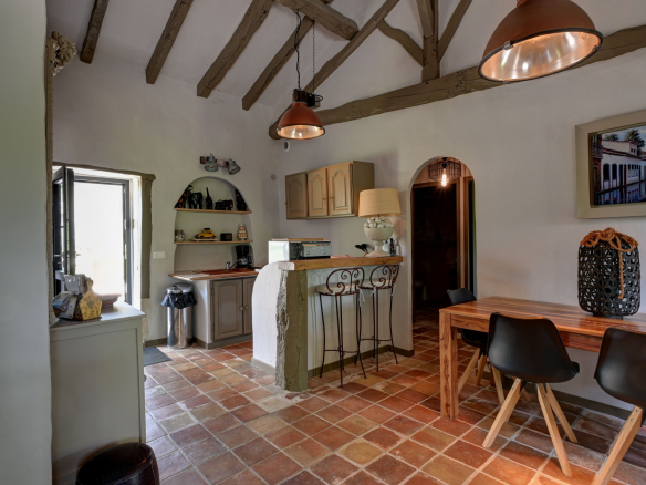 Interior of a house with open kitchen and dining room, stone walls and exposed beams.