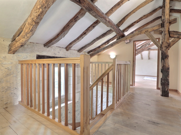 Intérieur d'une maison avec poutres apparentes et un escalier en bois.