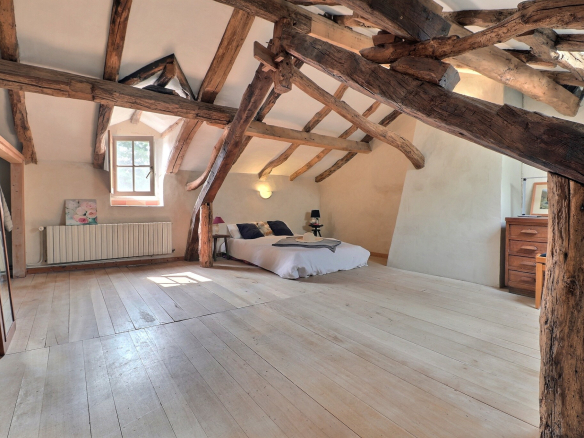 Intérieur d'une maison avec des poutres en bois apparentes et un sol en bois clair.