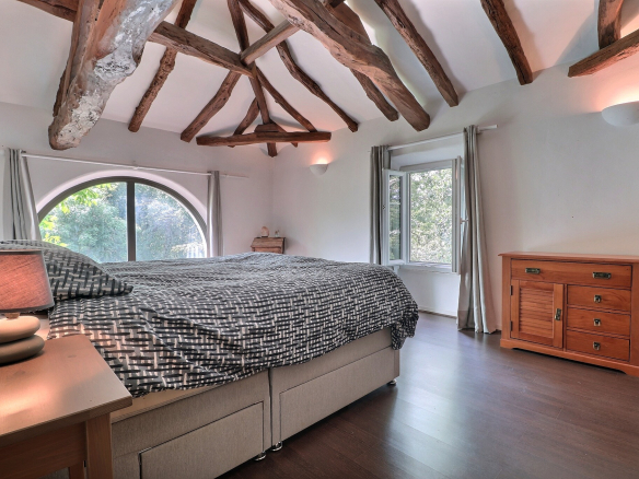 Chambre avec lit double et poutres apparentes dans une maison de Villeneuve-sur-Lot.