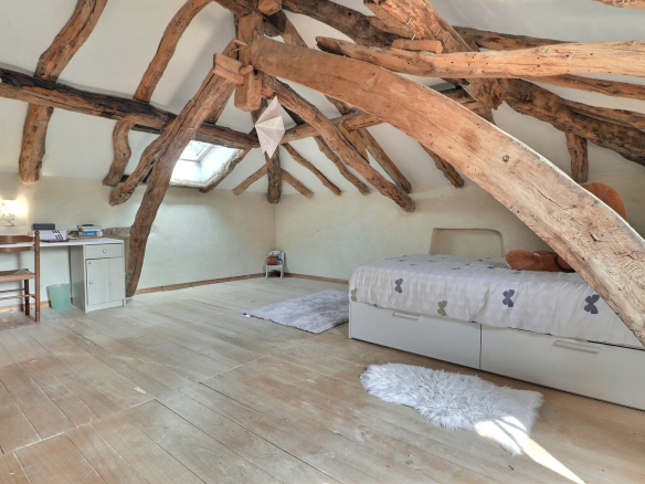 Intérieur d'une chambre avec poutres apparentes et parquet en bois.